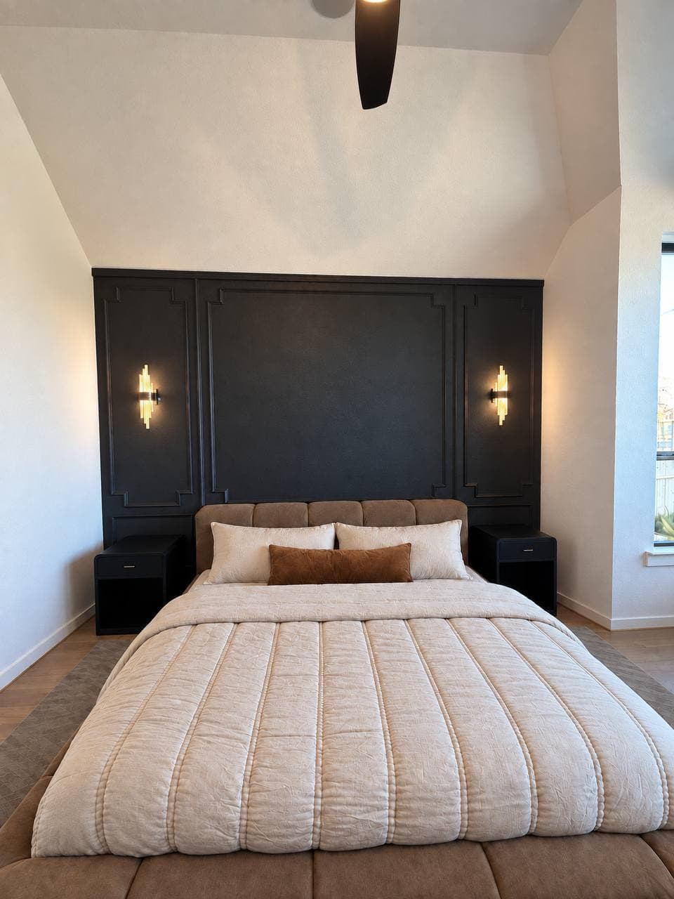 Bedroom feature wall in black applied panel moulding behind the bed, with two wall sconces and floating nightstands.